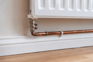 Heating pipes beneath a radiator expanding as they warm